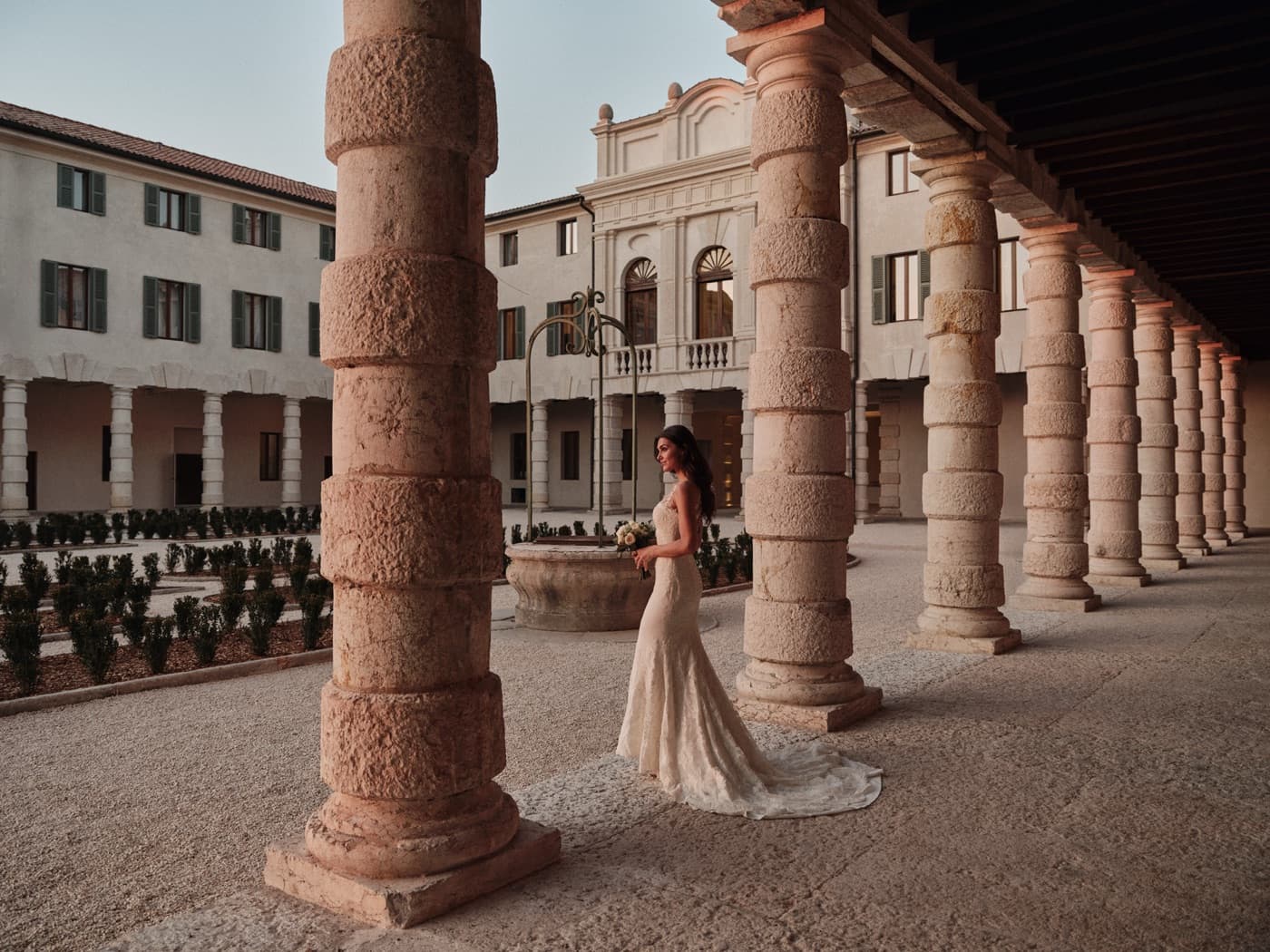 La sposa cammina lungo il loggiato tra le colonne di pietra