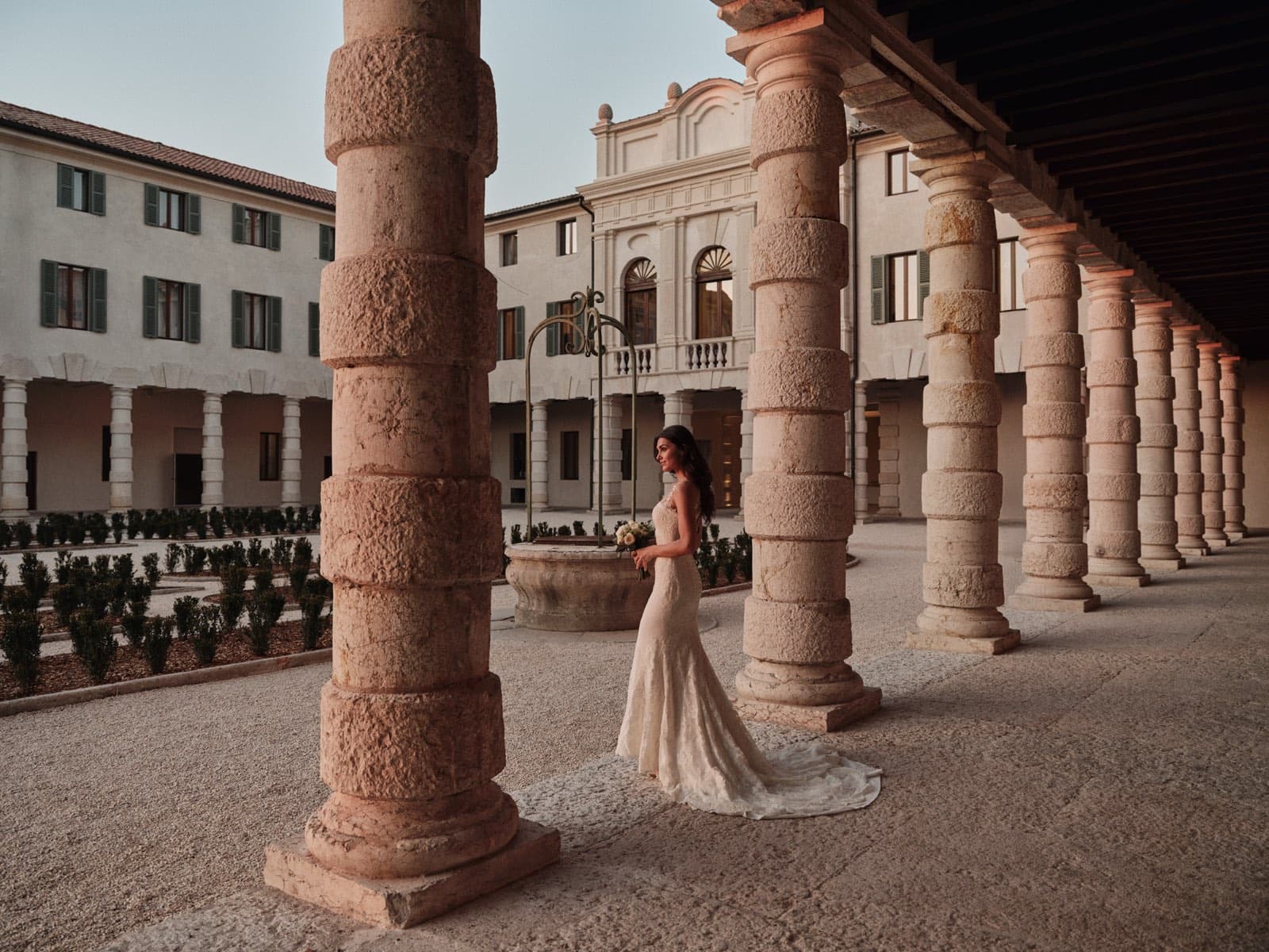 La sposa cammina lungo il loggiato tra le colonne di pietra